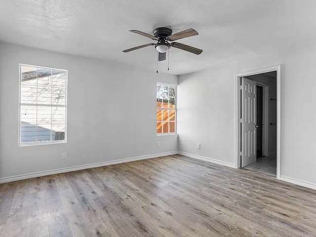 unfurnished bedroom with baseboards, ensuite bath, ceiling fan, and wood finished floors