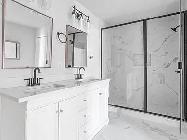 bathroom with a sink, a marble finish shower, double vanity, and marble finish floor