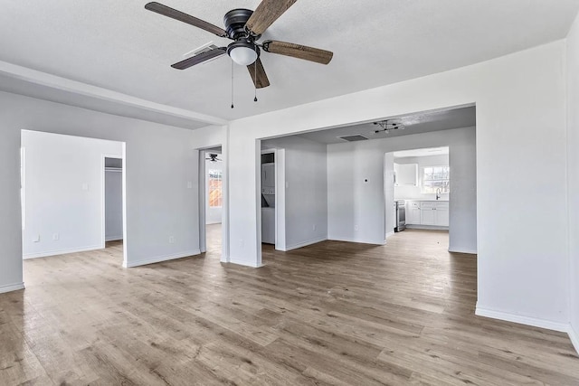 unfurnished living room featuring ceiling fan, visible vents, baseboards, and light wood-type flooring