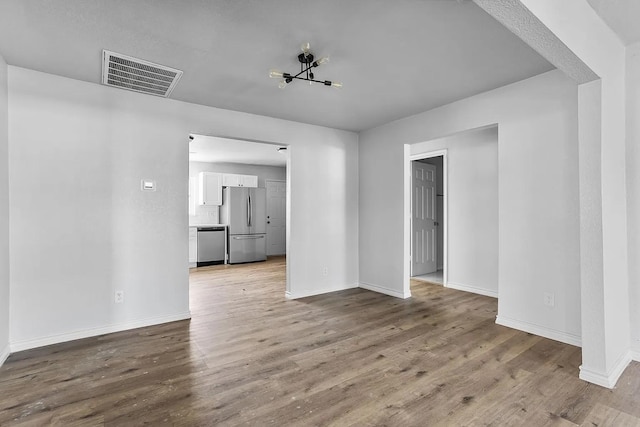 unfurnished room featuring visible vents, baseboards, and wood finished floors
