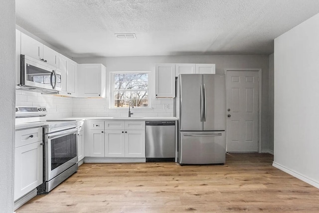 kitchen with a sink, a textured ceiling, tasteful backsplash, and stainless steel appliances