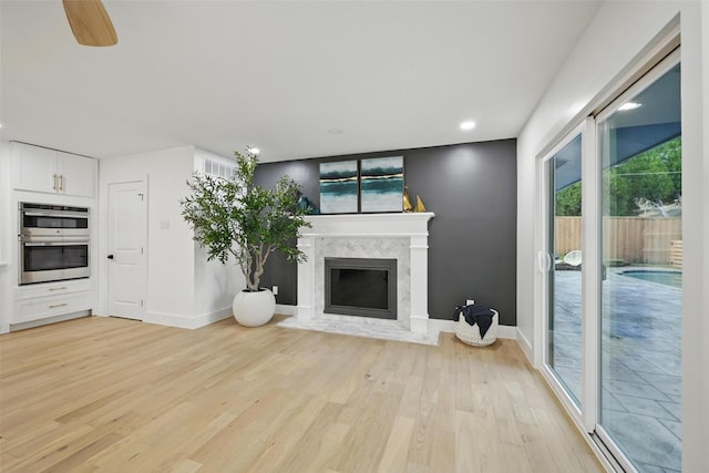 unfurnished living room featuring baseboards, visible vents, light wood finished floors, and a premium fireplace