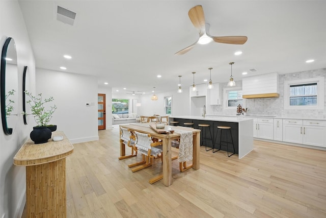 kitchen featuring light wood-style floors, premium range hood, white cabinetry, and visible vents