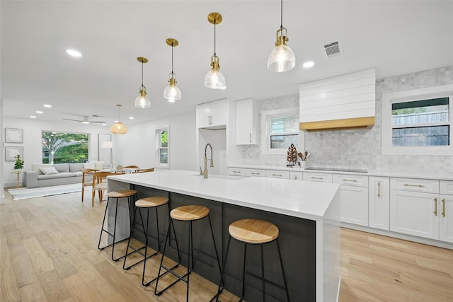 kitchen with backsplash, white cabinetry, visible vents, and light wood-type flooring