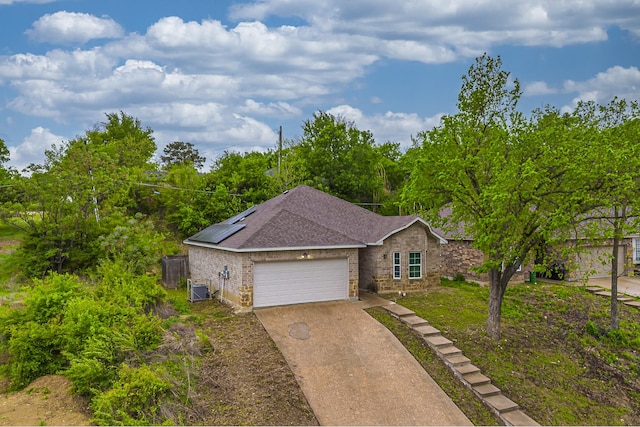 2801 17th St, Fort Worth, TX 76106 - ranch-style home featuring roof with shingles, an attached garage, brick siding, roof mounted solar panels, and concrete driveway