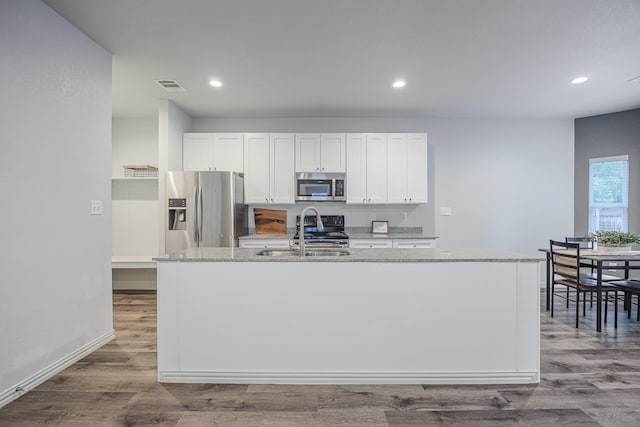 2801 17th St, Fort Worth, TX 76106 - kitchen featuring white cabinets, appliances with stainless steel finishes, a center island with sink, and visible vents