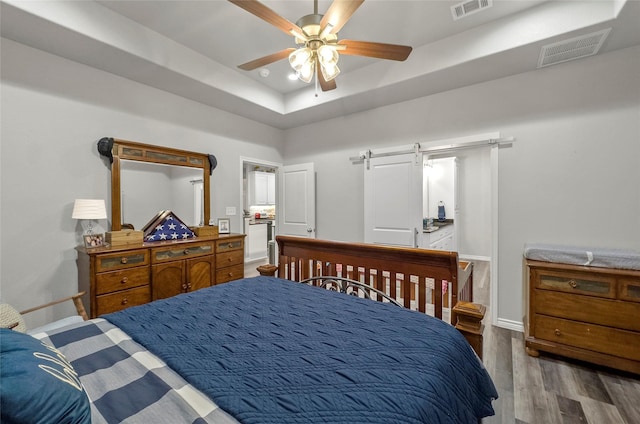 141 Walnut St, Paradise, TX 76073 - bedroom featuring wood finished floors, baseboards, a barn door, a raised ceiling, and ceiling fan