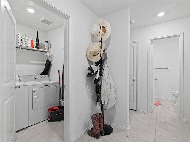 clothes washing area featuring laundry area, visible vents, baseboards, washing machine and clothes dryer, and light tile patterned floors