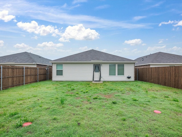 back of property featuring a fenced backyard, a lawn, and roof with shingles