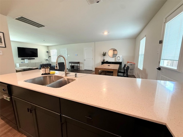 kitchen with visible vents, a sink, light stone counters, and open floor plan