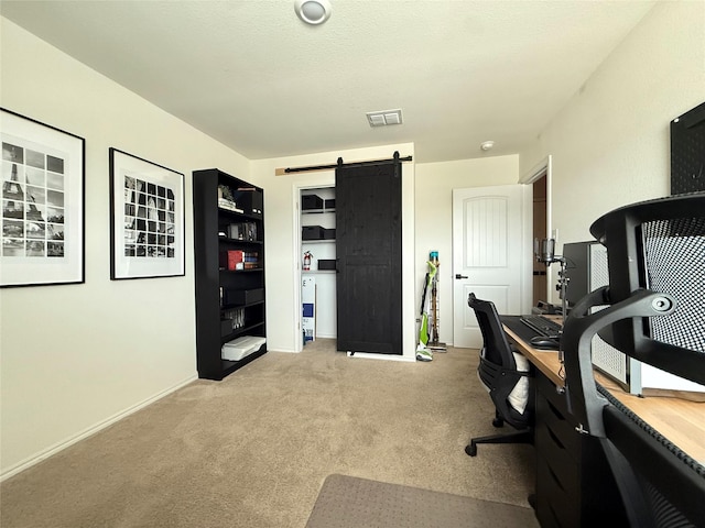 carpeted office space featuring baseboards, a barn door, and visible vents