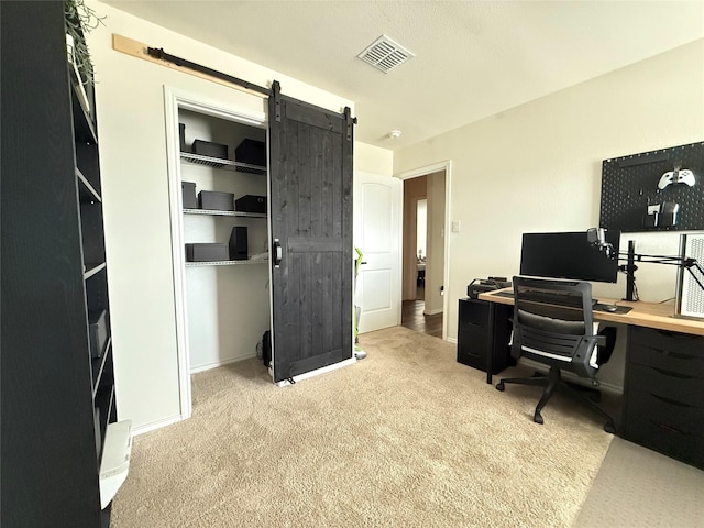 carpeted home office featuring baseboards, a barn door, and visible vents