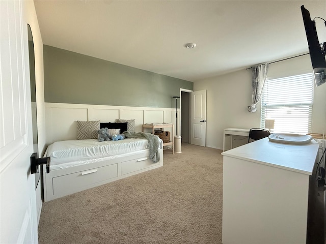 bedroom with light colored carpet and a wainscoted wall