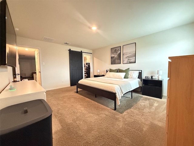 bedroom with a barn door, visible vents, light carpet, and baseboards