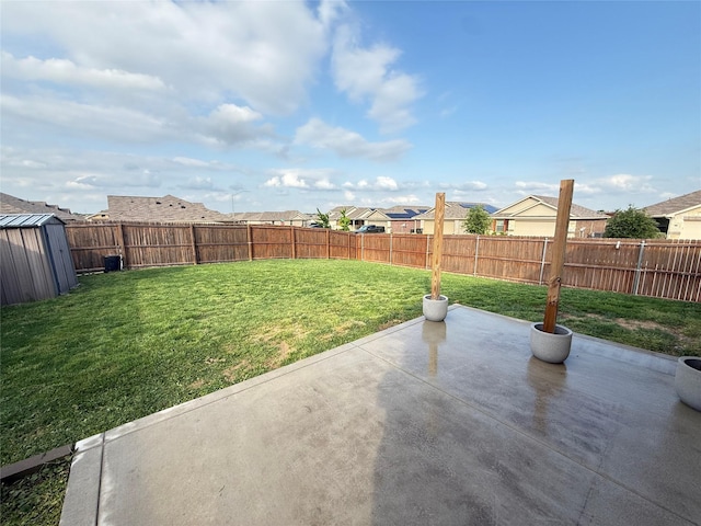 view of yard featuring a residential view, an outdoor structure, a fenced backyard, a storage unit, and a patio