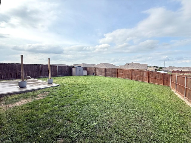 view of yard with a storage unit, a fenced backyard, a patio, and an outdoor structure