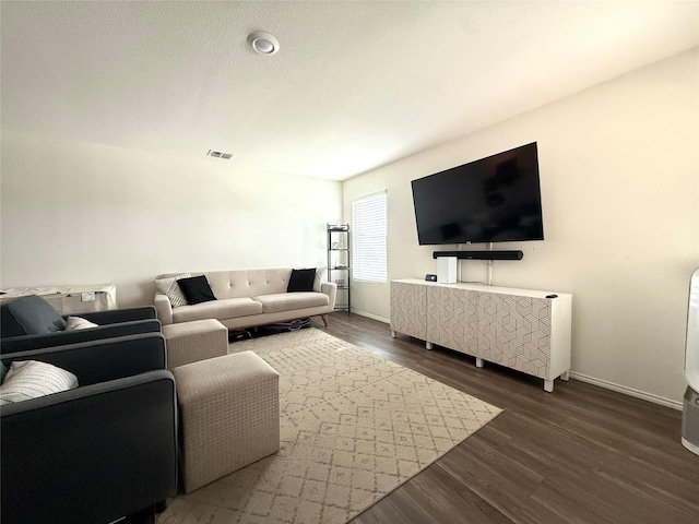 living area with baseboards, visible vents, and wood finished floors