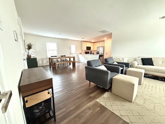 living area with visible vents and wood finished floors