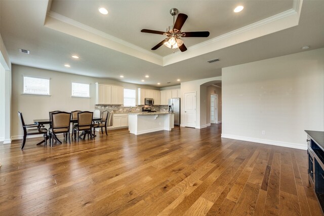 1130 Pasatiempo Dr, Frisco, TX 75036 - living room with a raised ceiling, arched walkways, ceiling fan, hardwood / wood-style floors, and ornamental molding