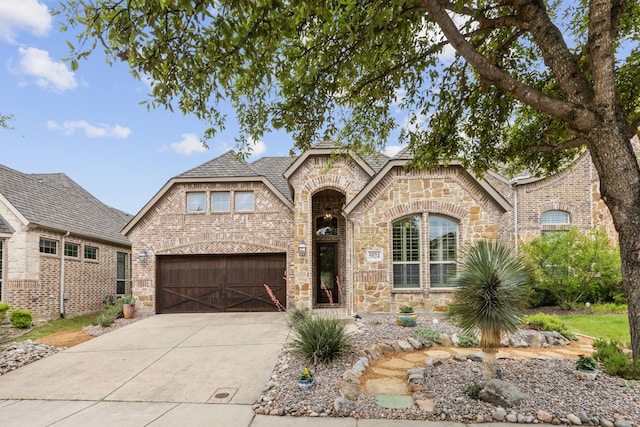 5924 Heron Bay Ln, Mckinney, TX 75070 - french country home featuring a garage, brick siding, concrete driveway, a shingled roof, and stone siding