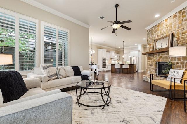 5924 Heron Bay Ln, Mckinney, TX 75070 - living area with crown molding, a ceiling fan, dark wood finished floors, a stone fireplace, and a chandelier