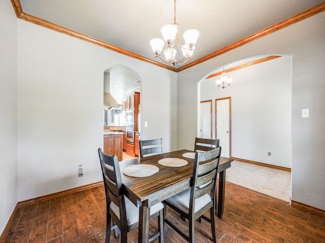 dining room featuring arched walkways, a chandelier, ornamental molding, and wood finished floors