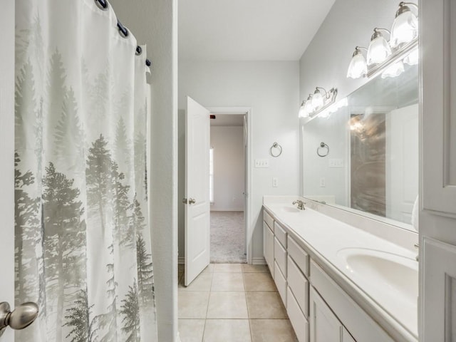 bathroom with tile patterned flooring, double vanity, a sink, and baseboards