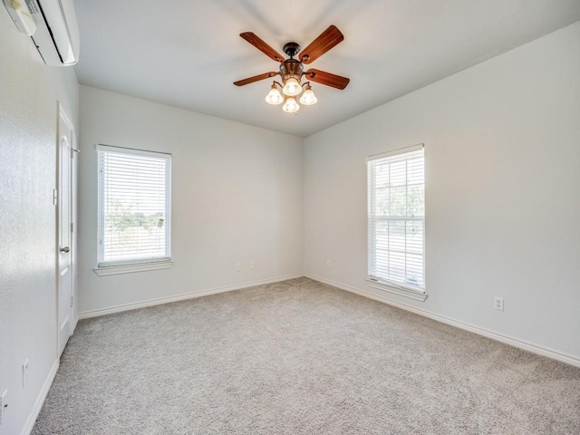 carpeted spare room featuring an AC wall unit, baseboards, ceiling fan, and a healthy amount of sunlight