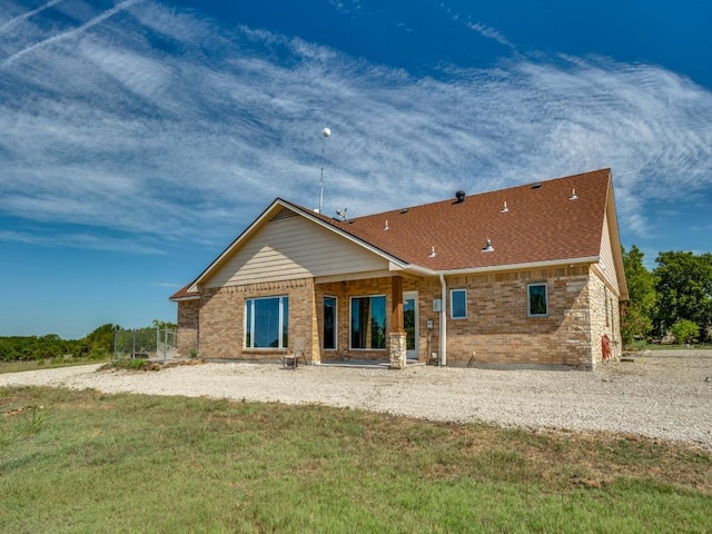 rear view of house featuring brick siding and a shingled roof