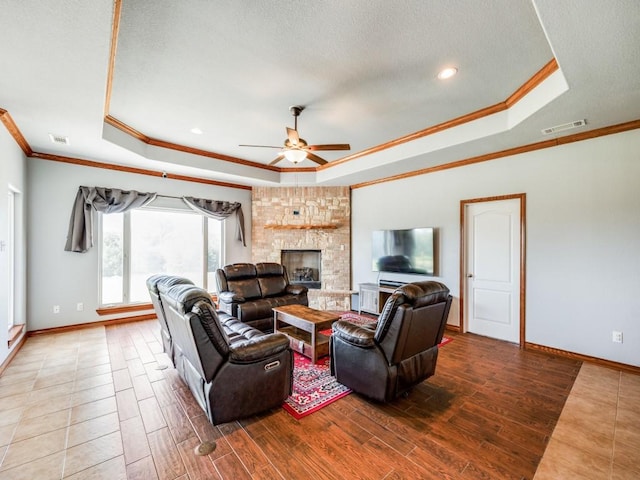 living area featuring wood tiled floor, ceiling fan, crown molding, baseboards, and a tray ceiling