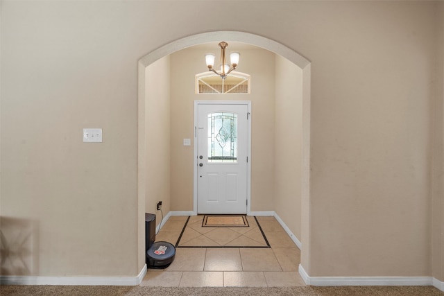 entryway featuring arched walkways, baseboards, a chandelier, and light tile patterned floors