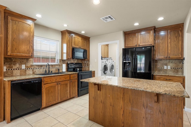kitchen with washer and dryer, a sink, tasteful backsplash, visible vents, and black appliances