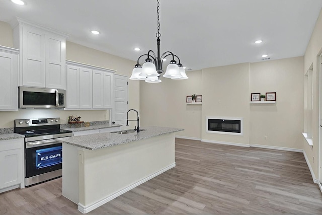 kitchen featuring a center island with sink, a sink, light wood finished floors, stainless steel appliances, and recessed lighting