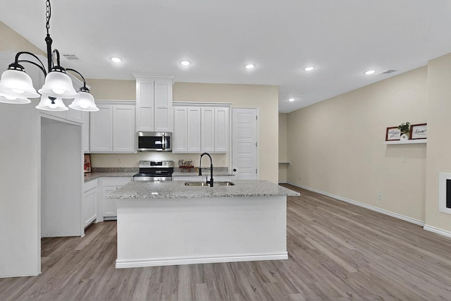 kitchen featuring light wood-style floors, a center island with sink, white cabinets, a sink, and stainless steel appliances