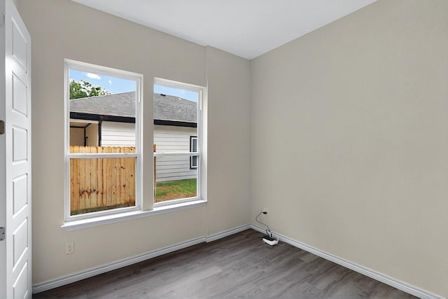 spare room with baseboards and wood finished floors
