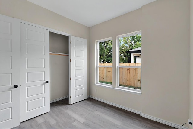 unfurnished bedroom with baseboards, wood finished floors, and a closet