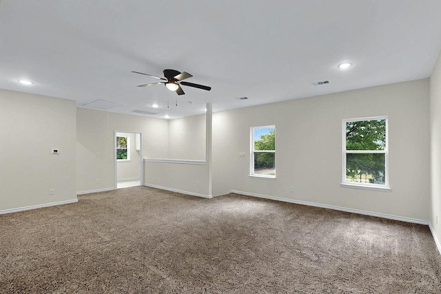 unfurnished room with visible vents, baseboards, attic access, a ceiling fan, and carpet