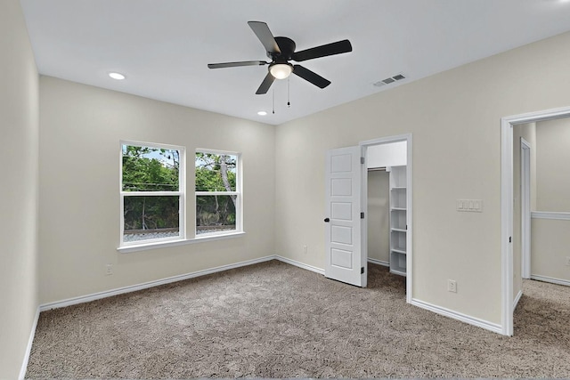unfurnished bedroom with baseboards, ceiling fan, carpet, and a spacious closet