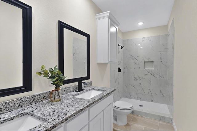 bathroom featuring double vanity, toilet, a sink, and a stall shower