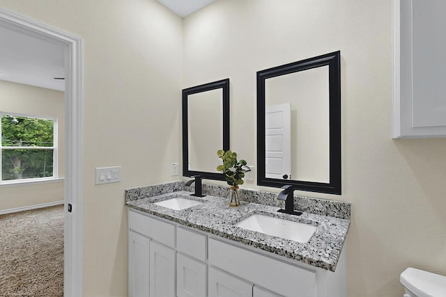 bathroom featuring a sink, toilet, and double vanity