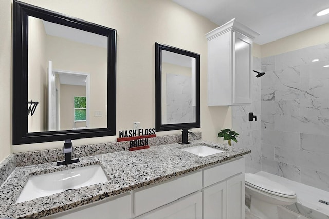 full bath featuring double vanity, a sink, toilet, and a shower stall