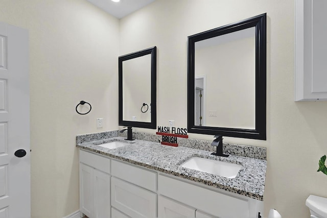 bathroom featuring double vanity, a sink, and toilet