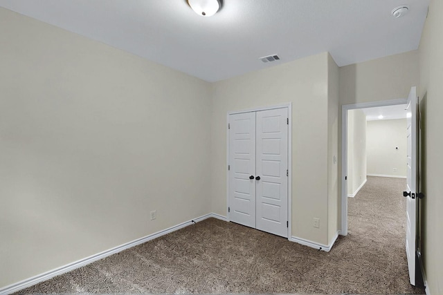unfurnished bedroom featuring visible vents, carpet flooring, baseboards, and a closet
