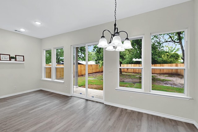 unfurnished dining area with visible vents, wood finished floors, baseboards, a notable chandelier, and recessed lighting