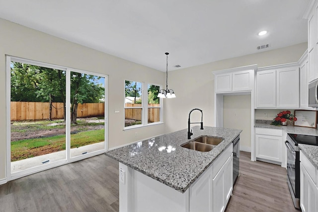 kitchen with visible vents, electric range oven, light wood-type flooring, a sink, and white cabinets