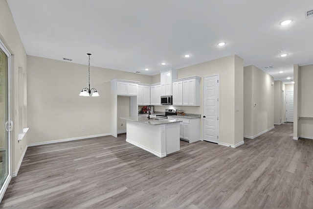 kitchen with appliances with stainless steel finishes, a sink, light wood-style floors, baseboards, and visible vents