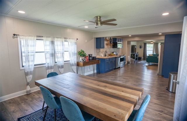 dining room featuring baseboards, ornamental molding, a ceiling fan, and dark wood-style flooring