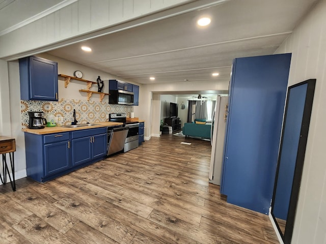 kitchen with a sink, wooden counters, dark wood-style floors, blue cabinets, and stainless steel appliances