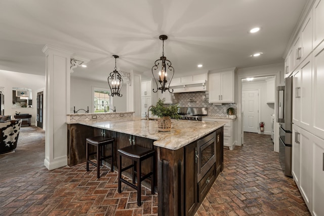 8121 Cahoba Dr, Fort Worth, TX 76135 - kitchen featuring stainless steel appliances, brick flooring, decorative backsplash, a kitchen breakfast bar, and recessed lighting