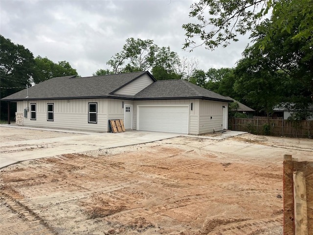 ranch-style home with fence, an attached garage, a shingled roof, board and batten siding, and driveway